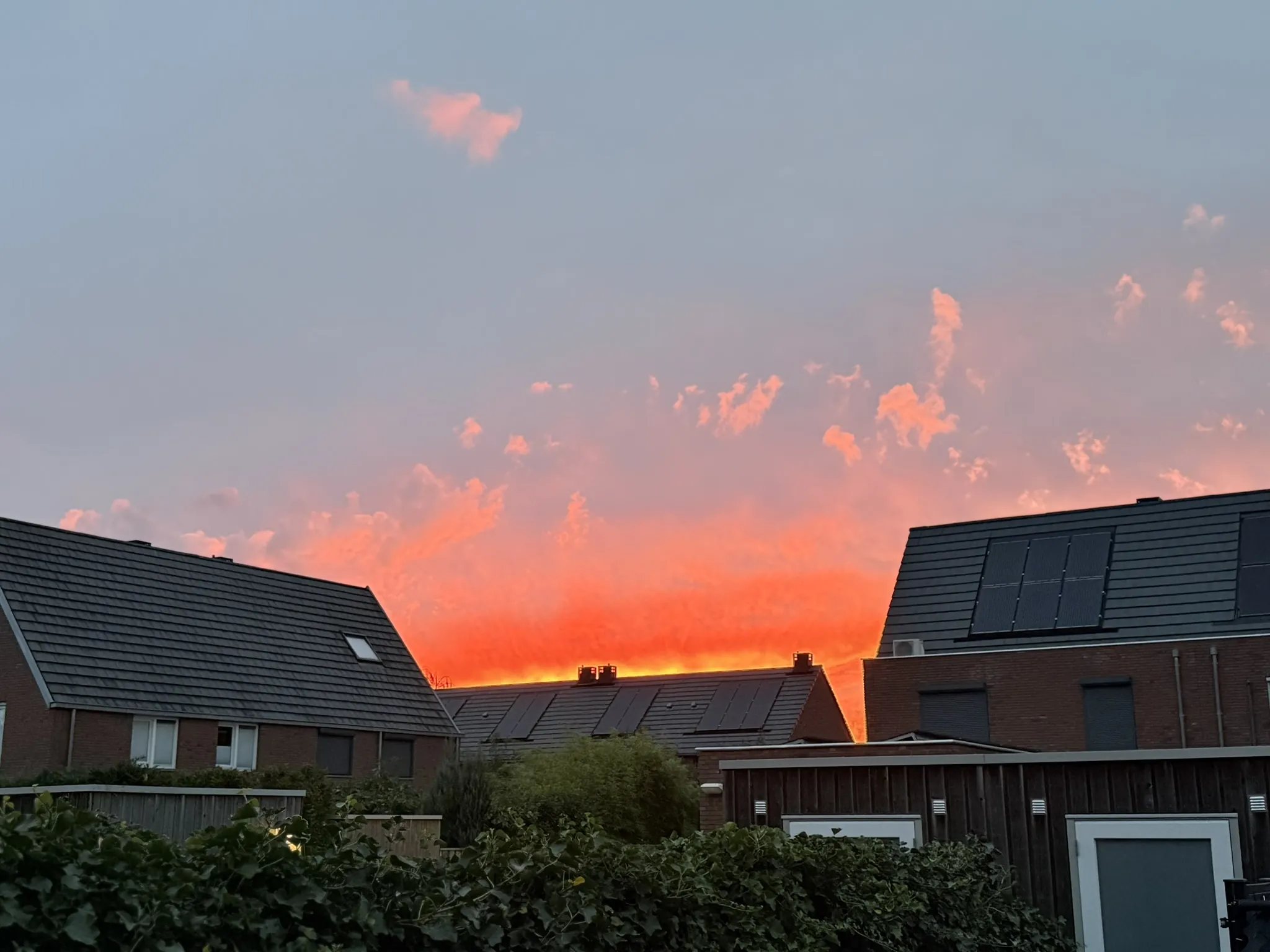 Orange evening sky over the rooftops of a Dutch residential street